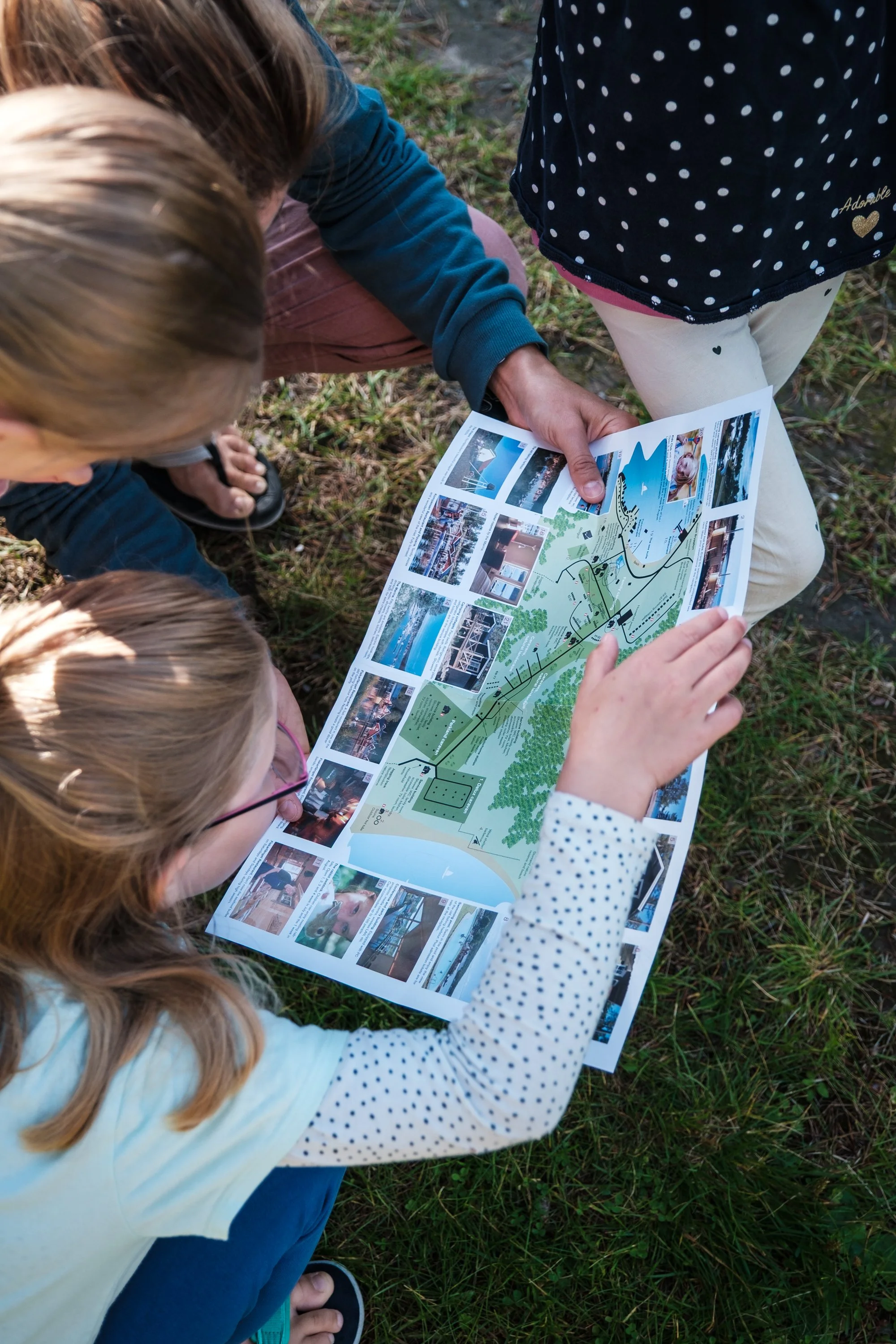Vier Kinder betrachten einen Stadtplan im Freien auf dem Gras.