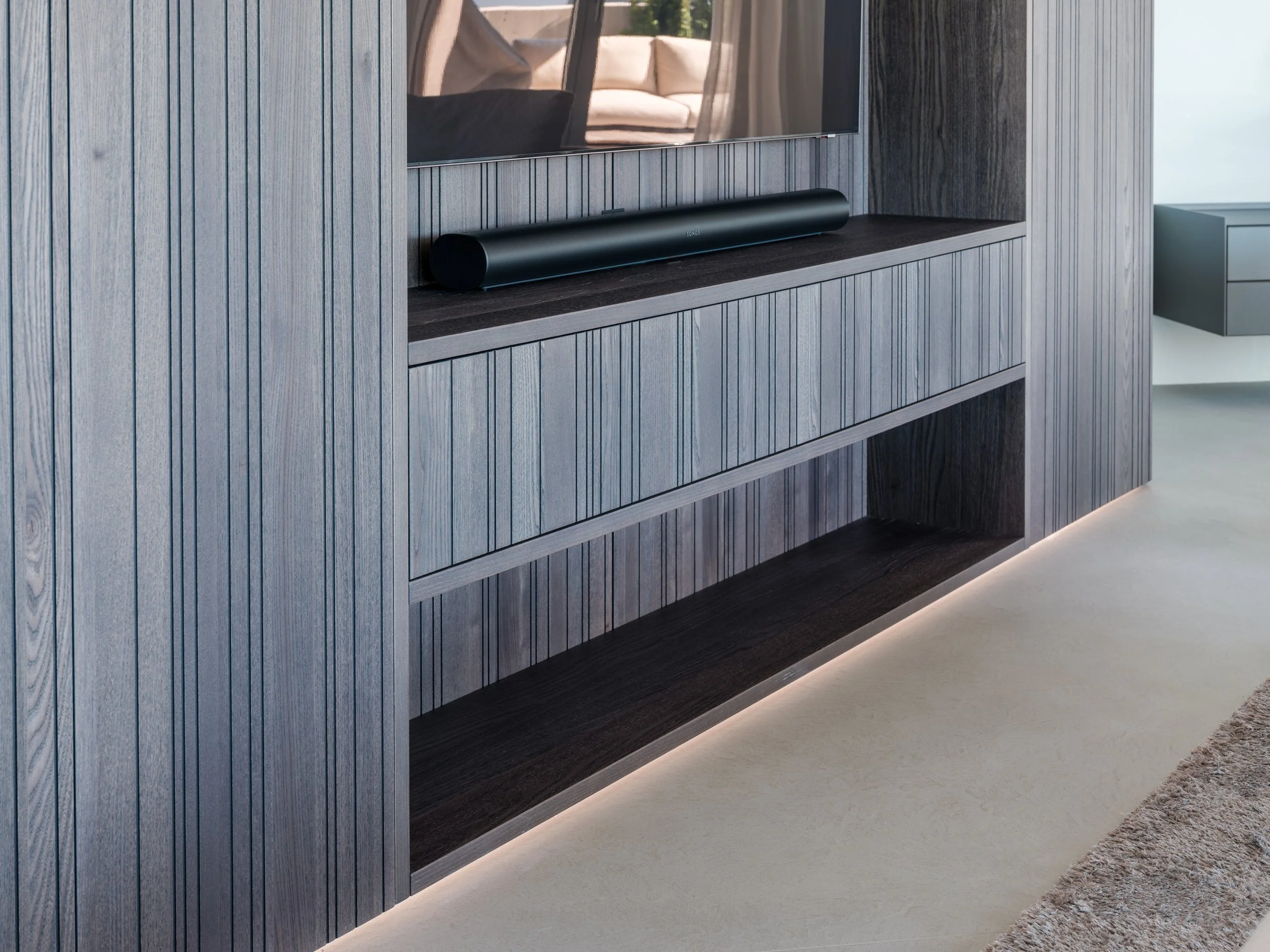 Moderne Wohnzimmerwand mit TV und schwarzem Lautsprecher, Beleuchtung unter der Wand, Holzmuster