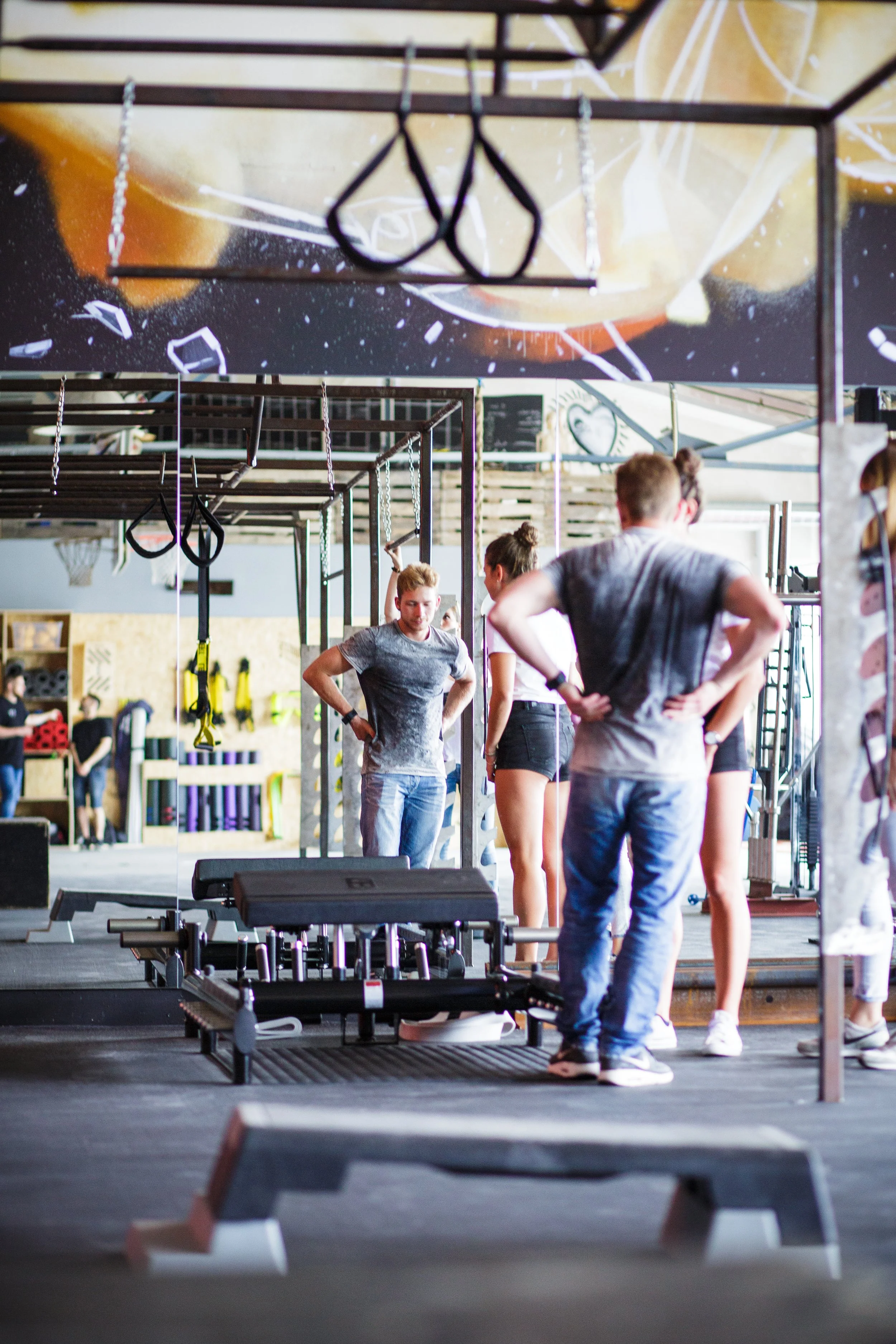 Menschen in einem Fitnessstudio, das mit Ringen, Hanteln und Fitnessgeräten ausgestattet ist, während sie sich auf eine Trainingseinheit vorbereiten.