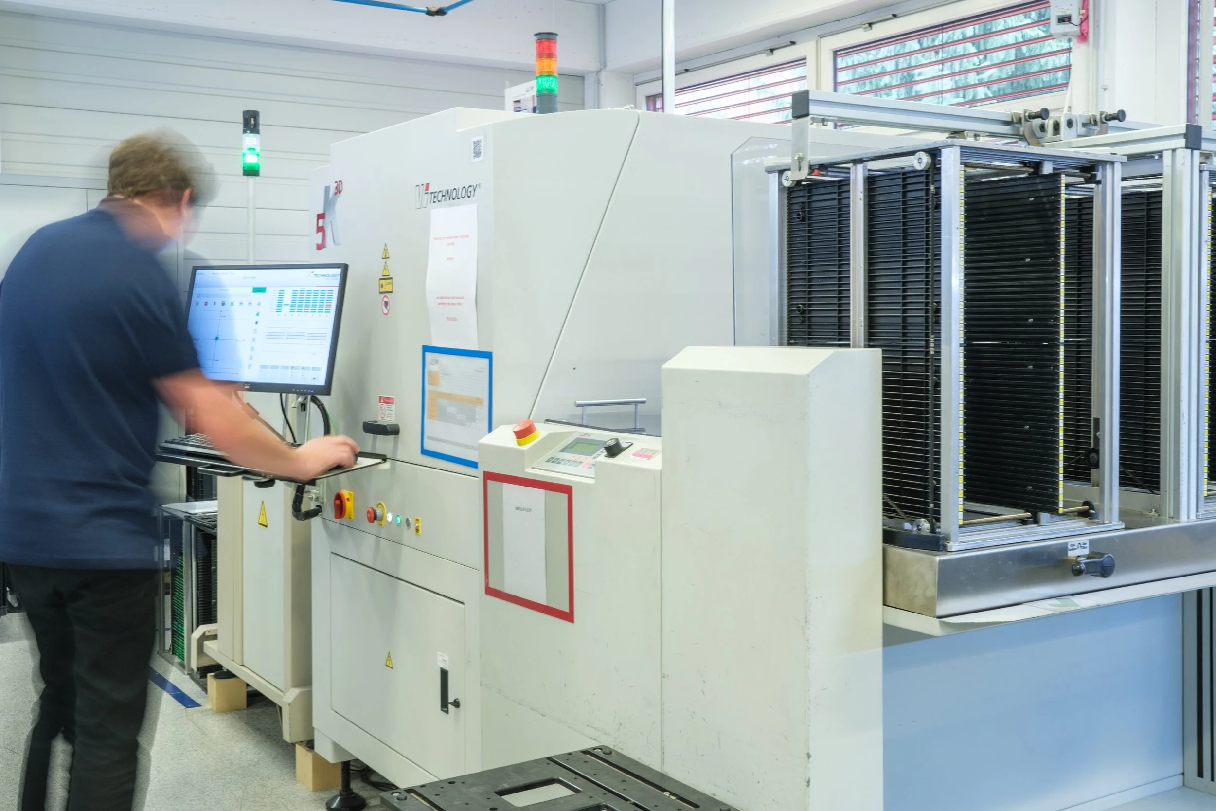 Mensch arbeitet an einer Maschine in einer technischen Fabrikhalle.